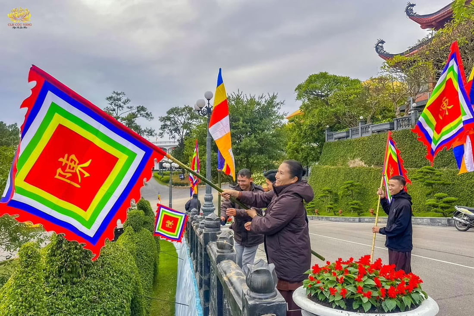 Cô hướng dẫn trang trí cờ thời Trần tại khu vực trước cổng Tam Quan của chùa