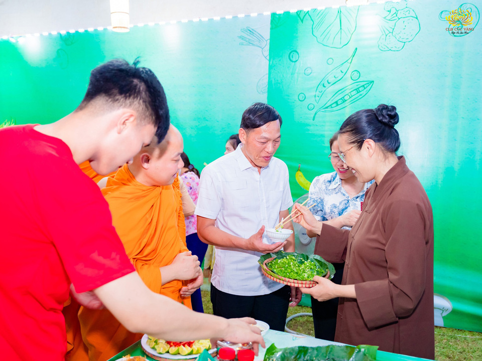 Cô Chủ nhiệm giới thiệu món ăn chay và mời ông Đinh Thuỷ Long - Chủ tịch xã Yên Hóa, huyện Minh Hóa thưởng thức ẩm thực tại gian hàng  